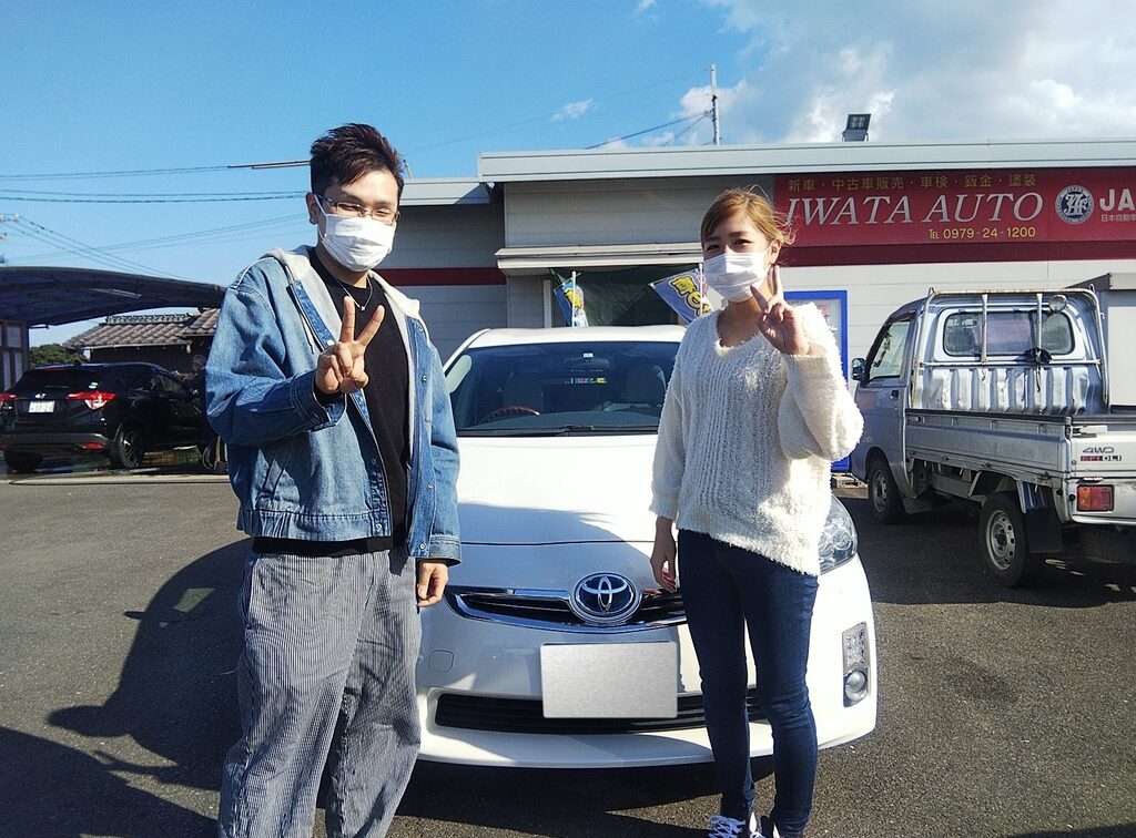 画像：白い車の前に立つ二人の男女