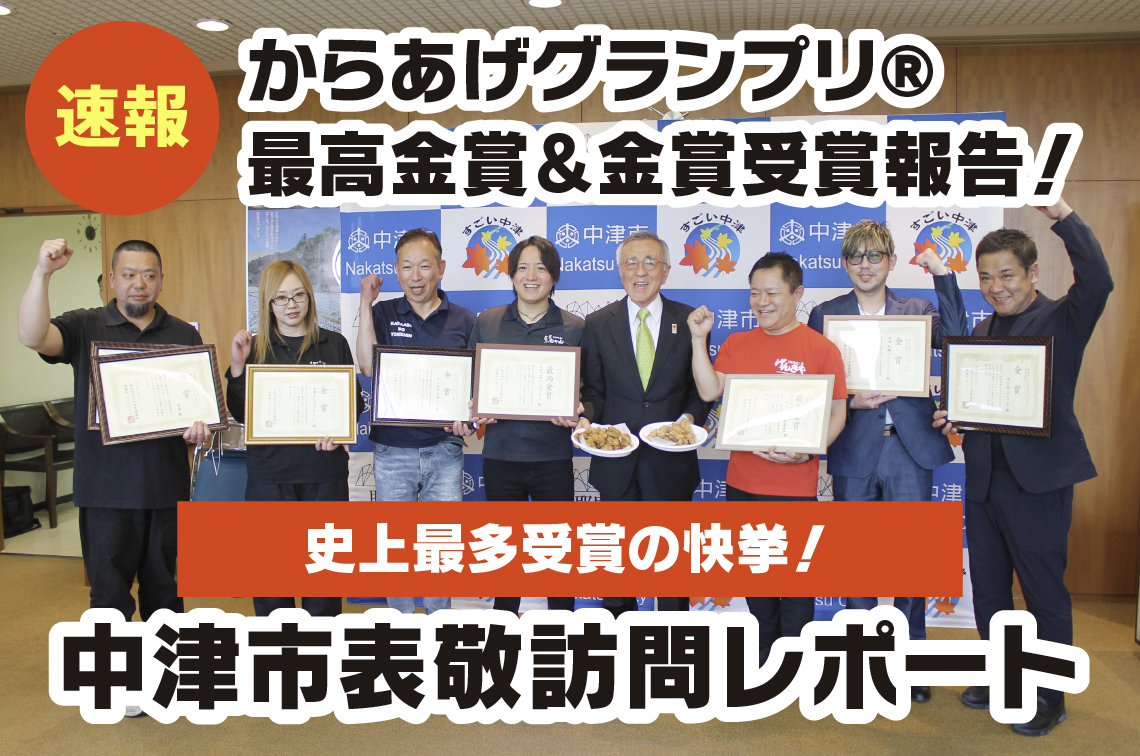 中津市役所にて、第17回からあげグランプリ最高金賞および金賞を受賞した市内7店舗の代表者が、奥塚市長を囲んで賞状を掲げる晴れやかな集合写真。