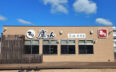 すし鷹りん鷹勝豊前店の外観。青空の下、「すし 鷹りん 鷹勝 豊前店」の看板が目を引く白い建物。手前にはテラススペースがあり、今後ビアガーデンとしてオープン予定
